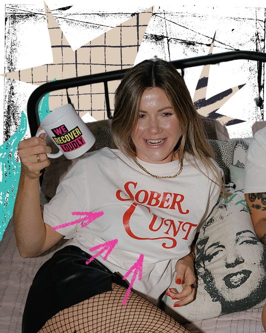 Person wearing a t-shirt with 'Sober Cunt' text, holding a mug, in a casual setting.